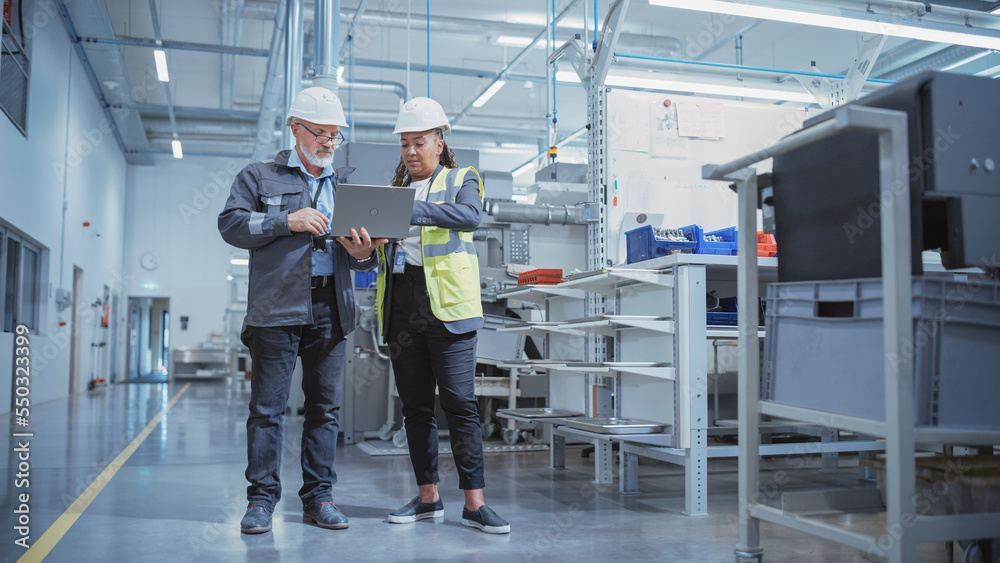 Portrait of Two Heavy Industry Employees in Hard Hats at Factory. Checking and Discussing Industrial