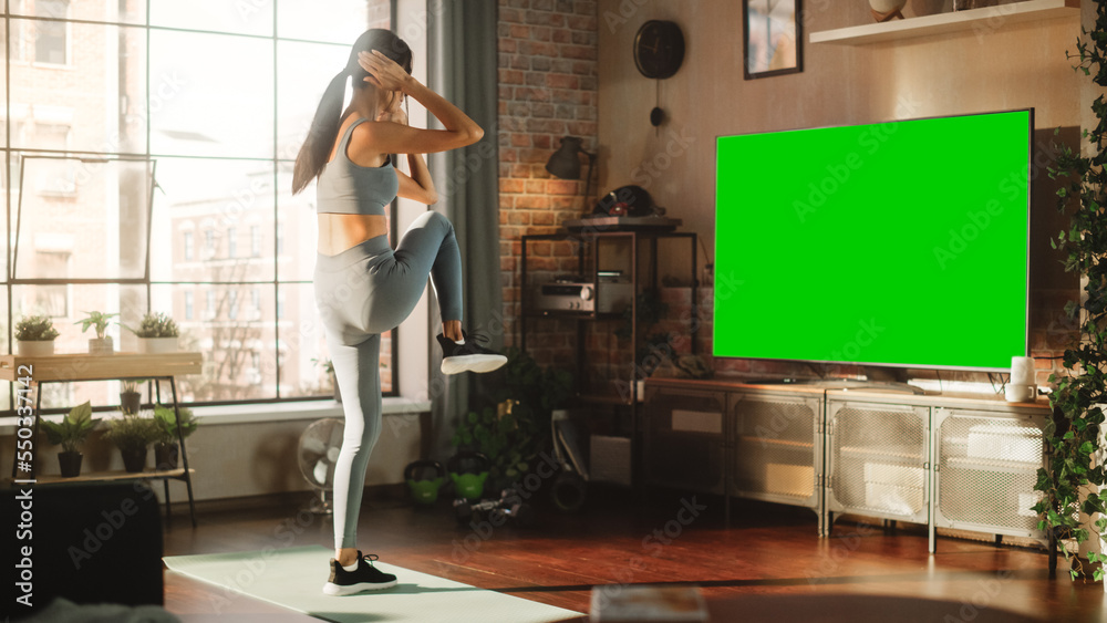 Active Girl Training at Home Using Green Mock-up TV Screen. Strong Athletic Fit Woman Using Technolo