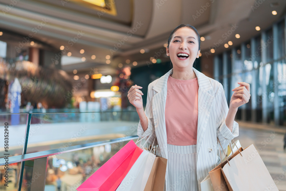 快乐微笑的亚洲女女孩拿着一堆购物袋，女性购物后回家