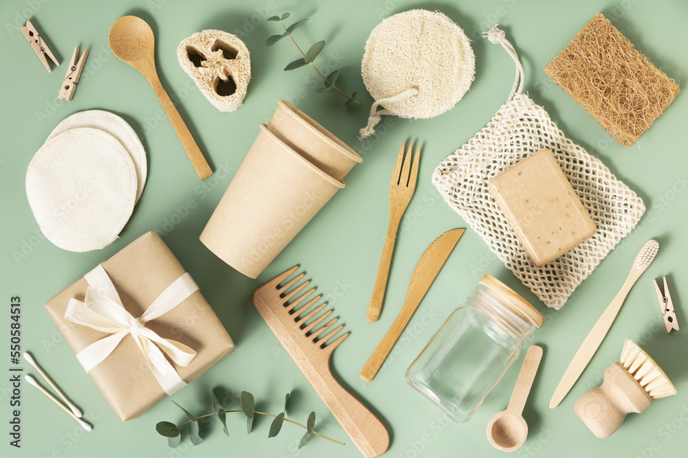 Set of eco-friendly tableware and cleaning products on pastel green background, flat lay stop plasti