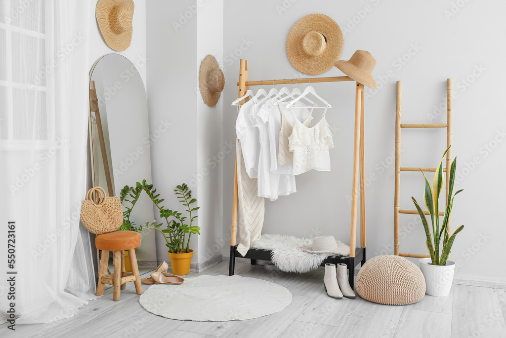 Interior of light dressing room with clothes, mirror and ladder