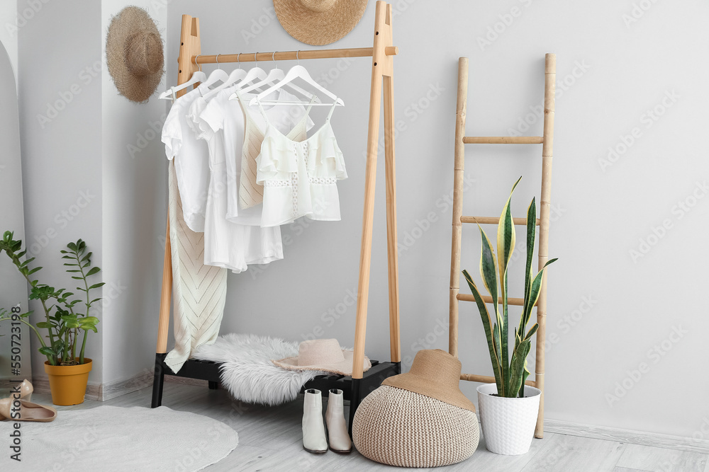 Interior of light dressing room with rack, clothes and ladder