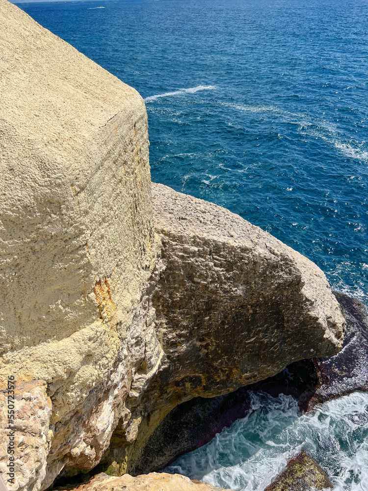 View of high cliff and sea water on sunny day