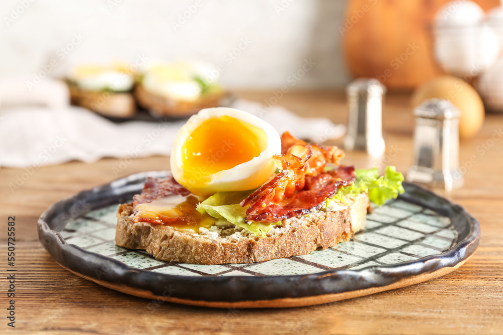 Plate of delicious toast with boiled egg and fried bacon on wooden table, closeup