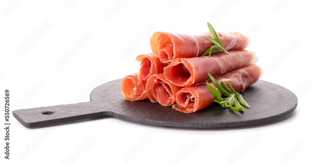 Slate board with rolled slices of tasty ham and rosemary on white background