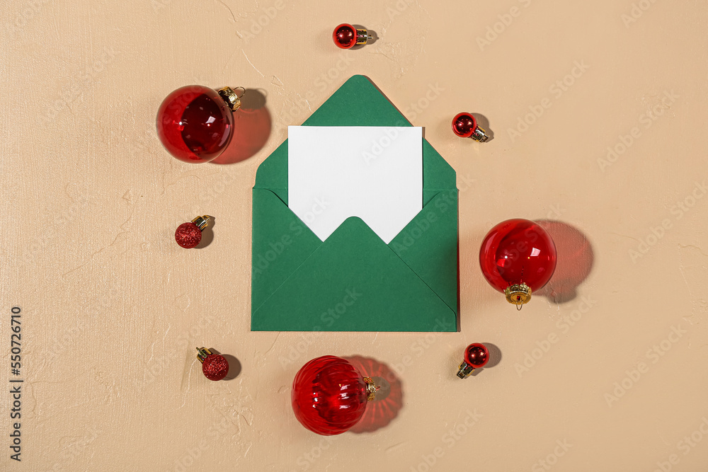 Envelope with blank card and Christmas balls on beige background