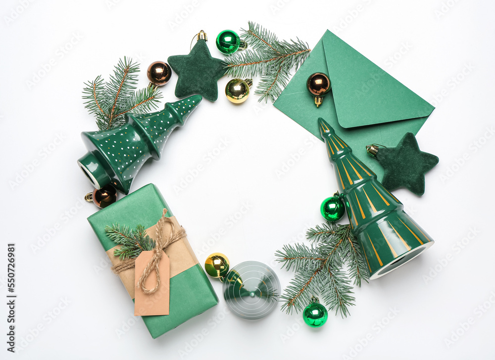 Frame made of Christmas branches, decor, envelope and gift on white background