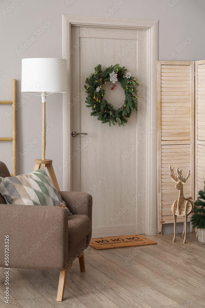 Door with Christmas wreath and wooden reindeer in light hall