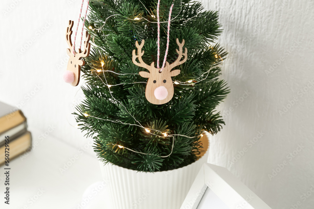 Small Christmas tree on table near light wall, closeup