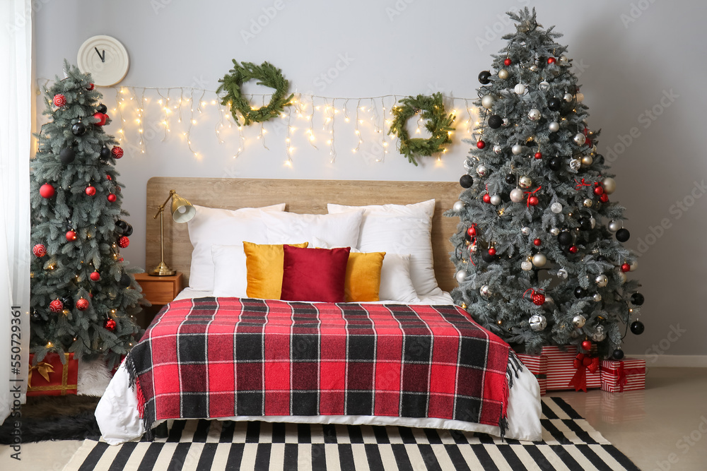 Interior of bedroom with Christmas trees, wreaths and glowing lights