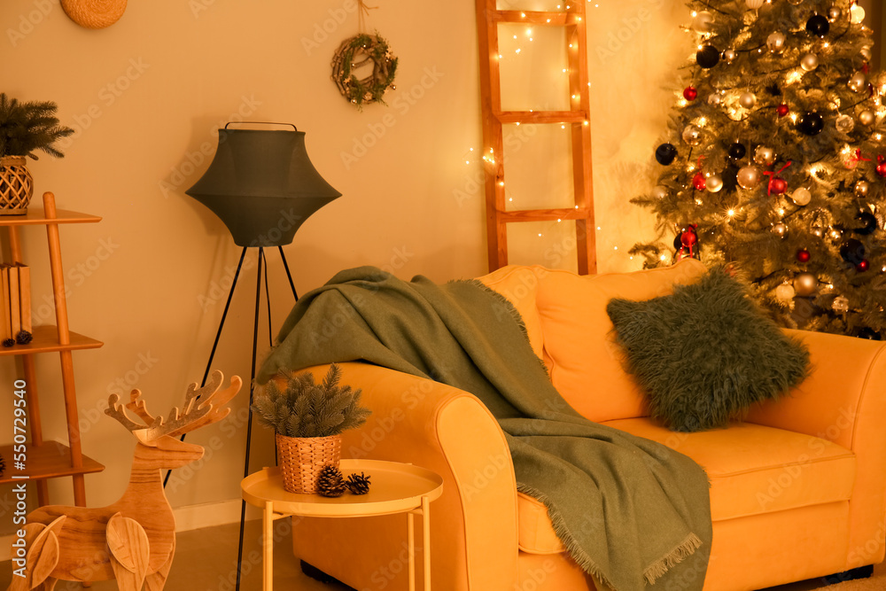 Interior of living room with sofa, Christmas tree and glowing lights at night