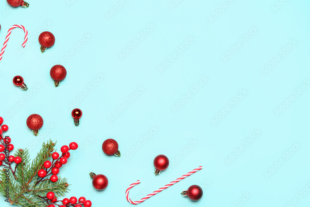 Christmas balls with candy canes, fir branches and viburnum berries on blue background