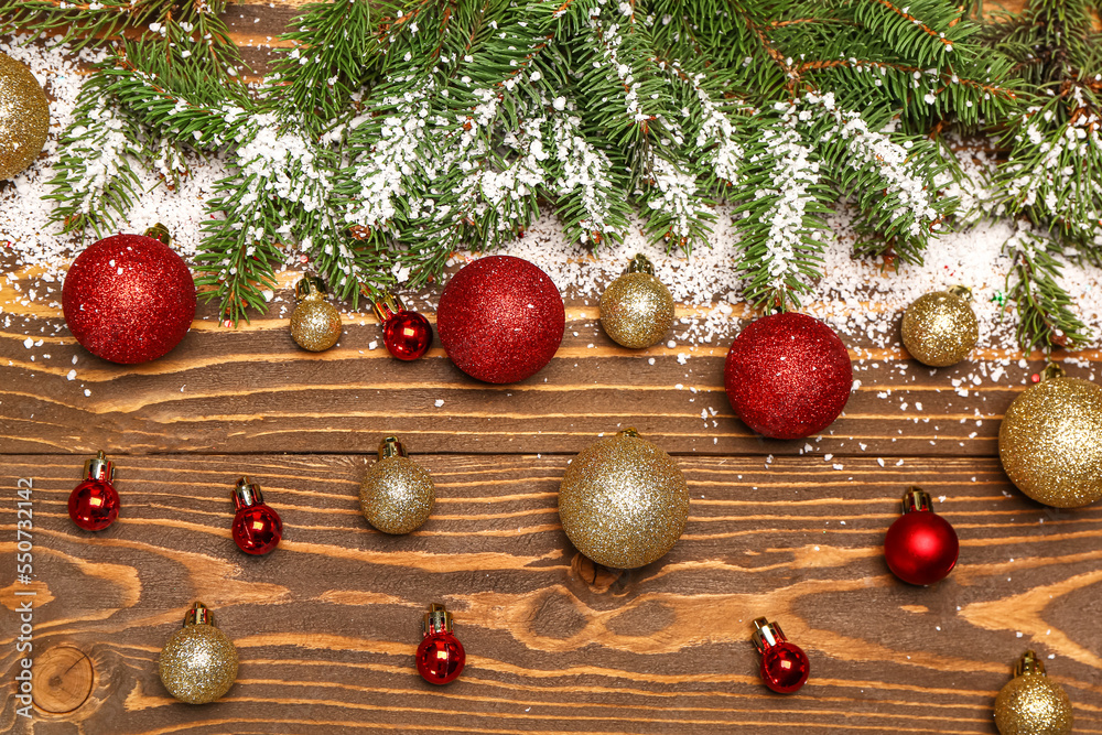 Fir branches with snow and Christmas balls on wooden background