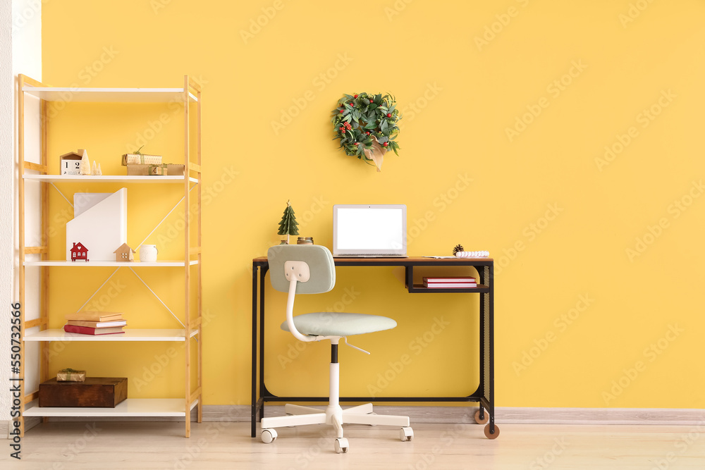 Interior of office with workplace, shelving unit and Christmas wreath