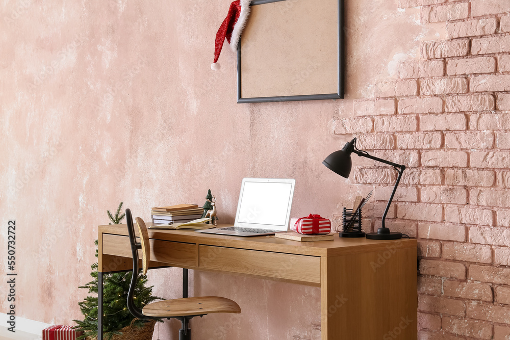 Workplace with laptop and Christmas gift near pink wall