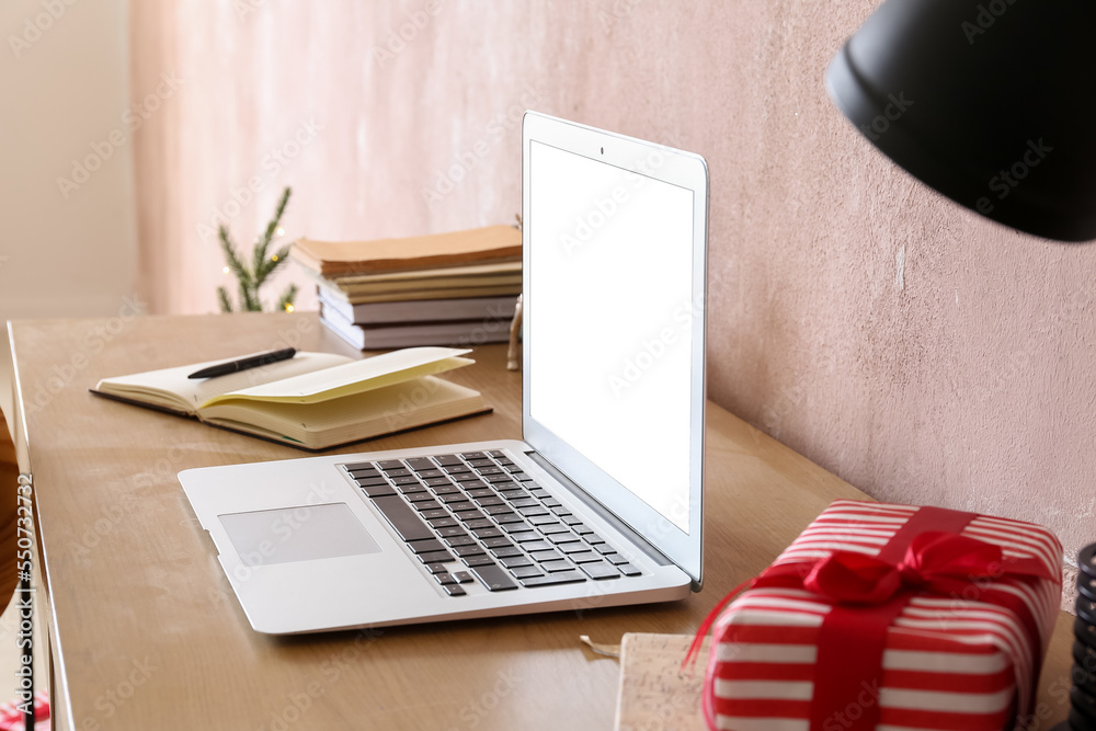 Laptop on table near pink wall, closeup