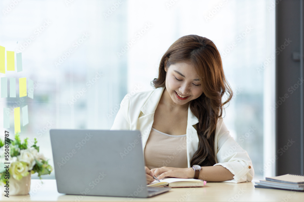 Charming Asian businesswoman working on a laptop in the office.