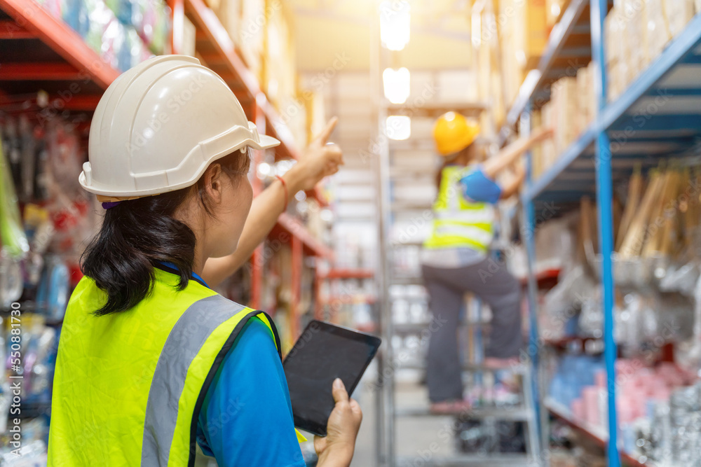 Asian teamwork of Foreman and female laborer working in a warehouse.  Working Woman Concept.