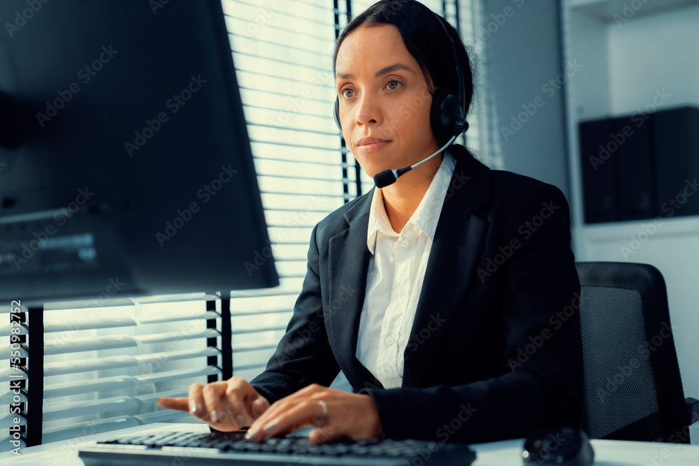 Competent female operator working on computer and talking with clients. Concept relevant to both cal