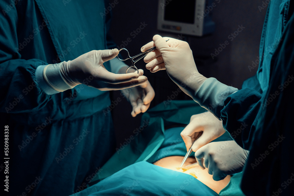 Image of surgical team perform surgery operation, nurse hand out sterile scissors to surgeon as supp