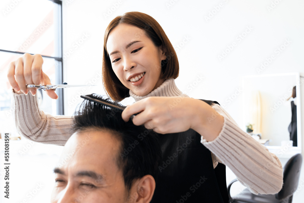 Closeup asian female barber making haircut for male customer with male hairstyle in qualified barber