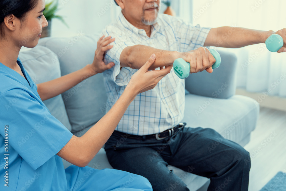 Contented senior patient doing physical therapy with the help of his caregiver. Senior physical ther