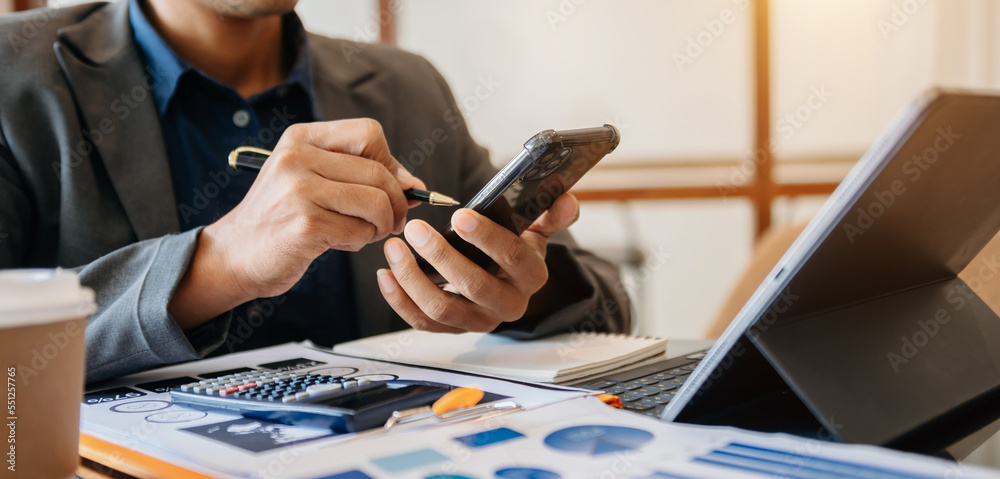 Confident businessman working on laptop and tablet at her workplace at modern office..