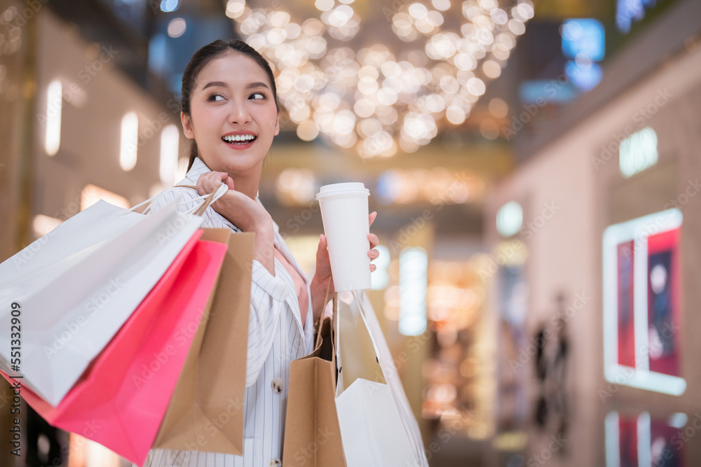 surprising cheerful asian female adult woman shopper hand hold shopping bag and coffee paper cup wal