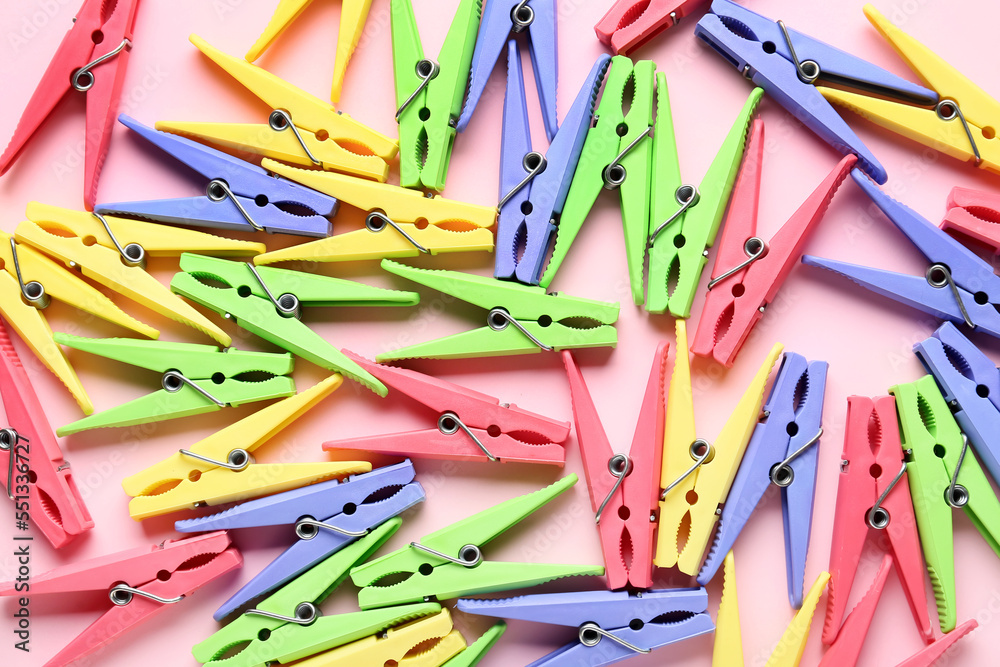 Different plastic clothespins on pink background, closeup