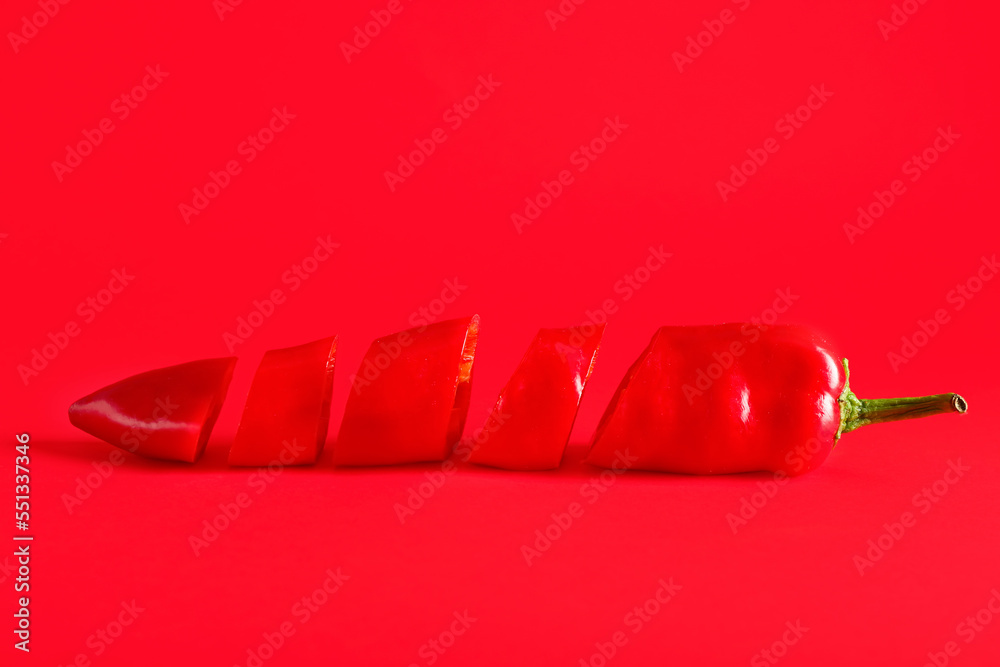 Cut chili pepper on red background