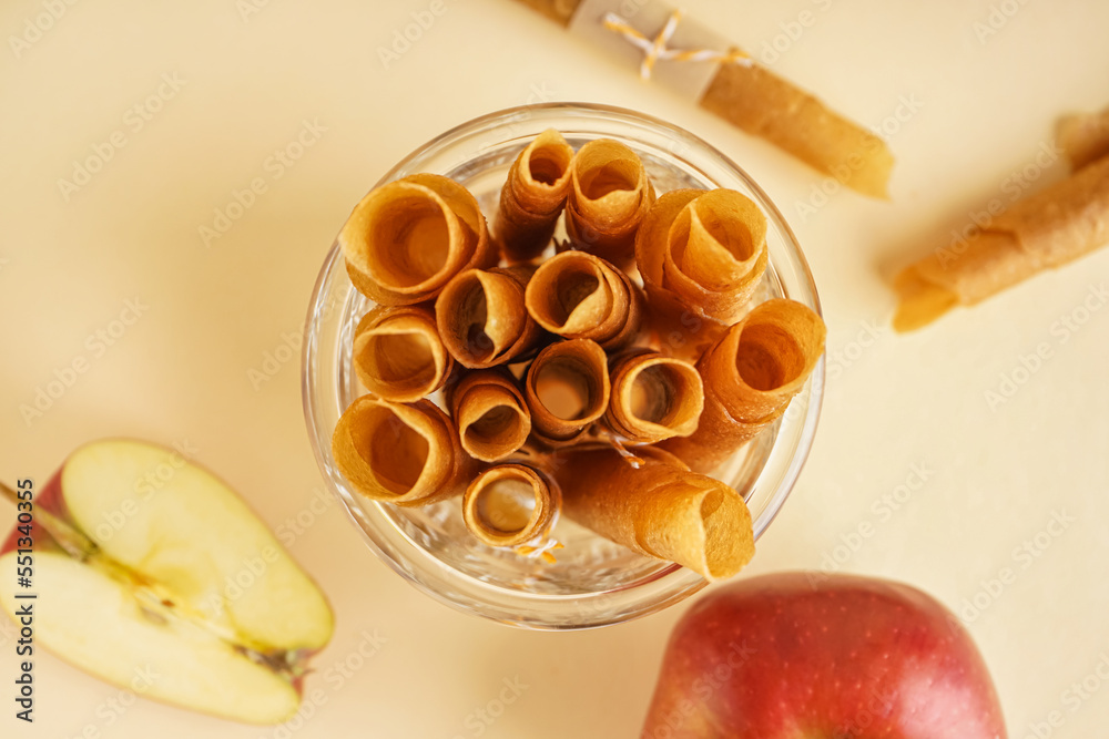 Glass with tasty apple pastilles on color background