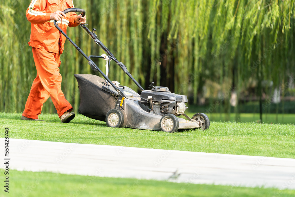 Worker is mowing the lawn 