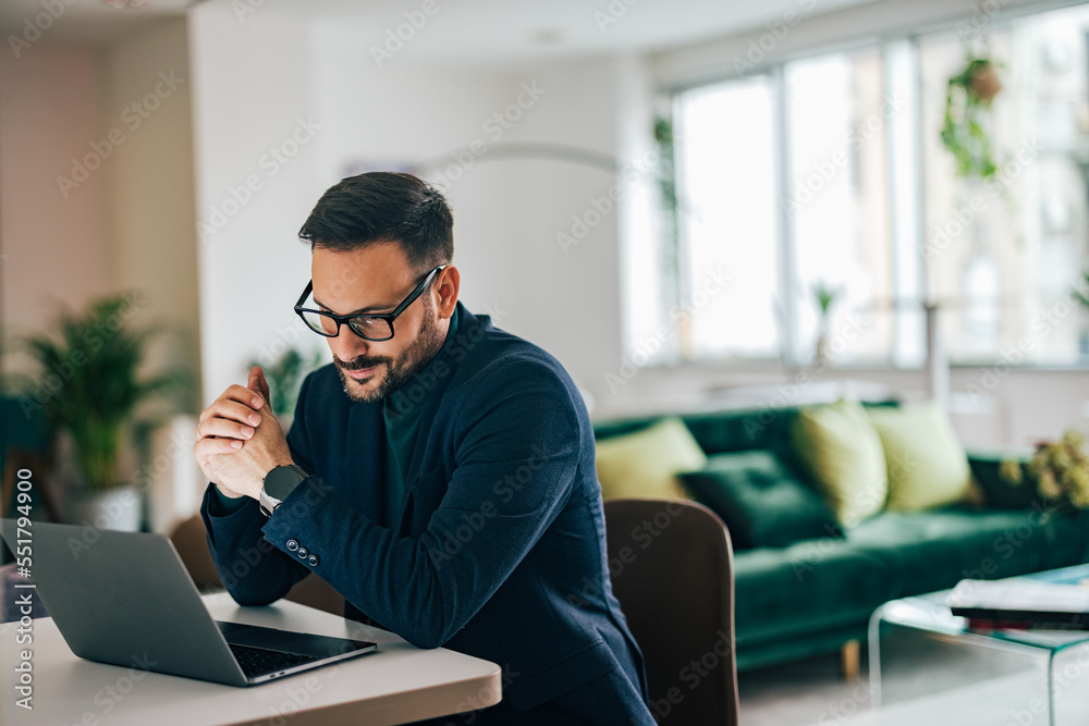 Adult businessman using a laptop while working from home.