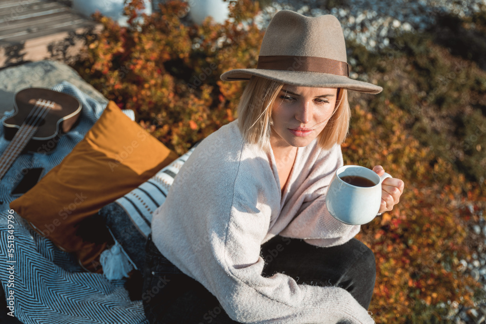 Beautiful woman in cowboy hat drinking coffee on patio in front of her house