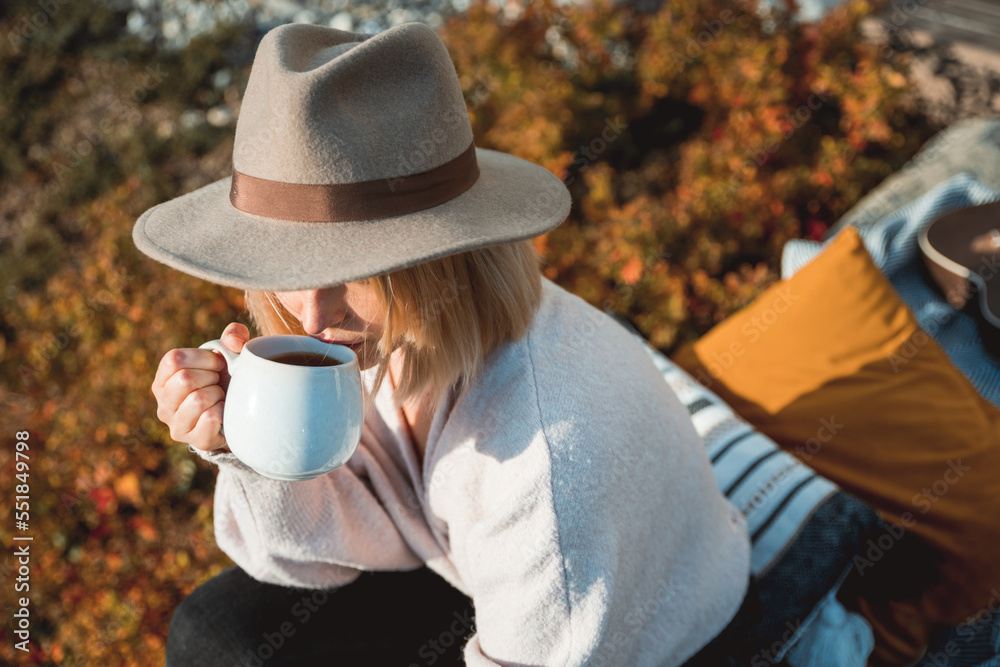 Beautiful woman in cowboy hat drinking coffee on patio in front of her house