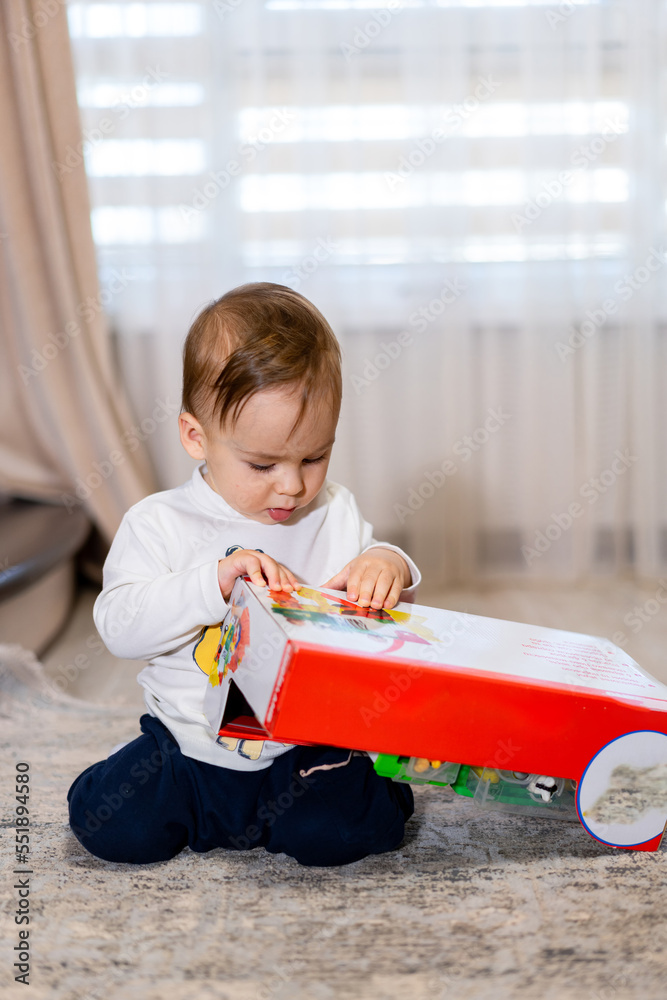 Little boy opening his birthday gift. Baby with new toy