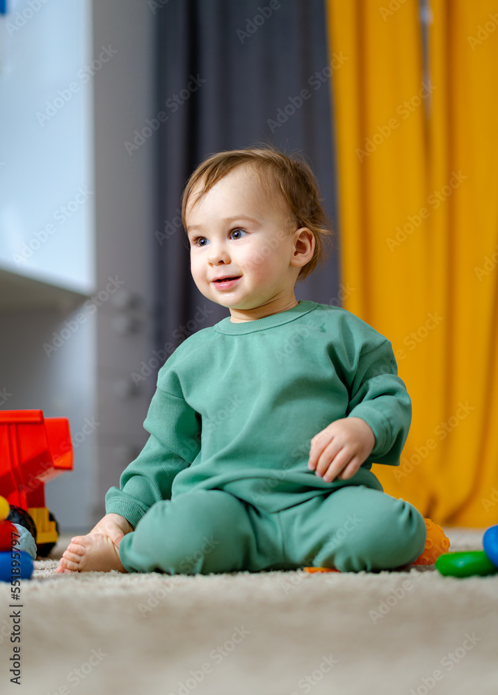 Baby boy playing with educational toy. Cute little boy is playing with toys while sitting on floor.