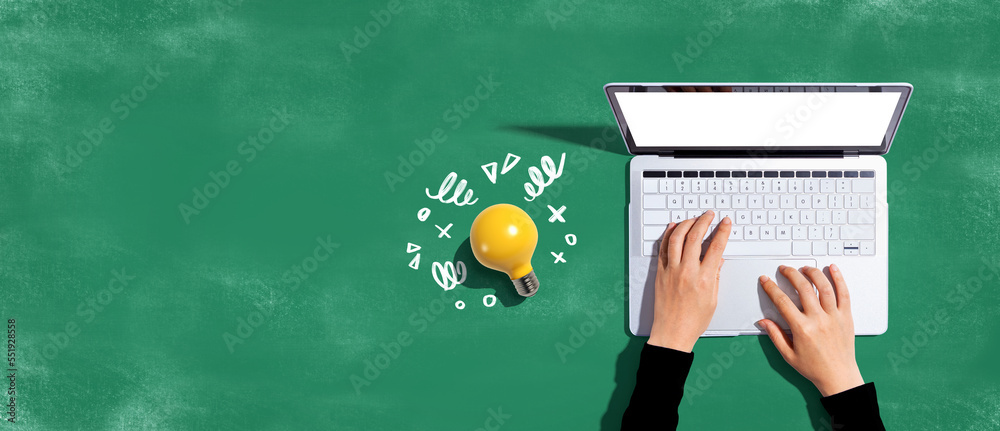 Person using a laptop computer and a light bulb - Flat lay