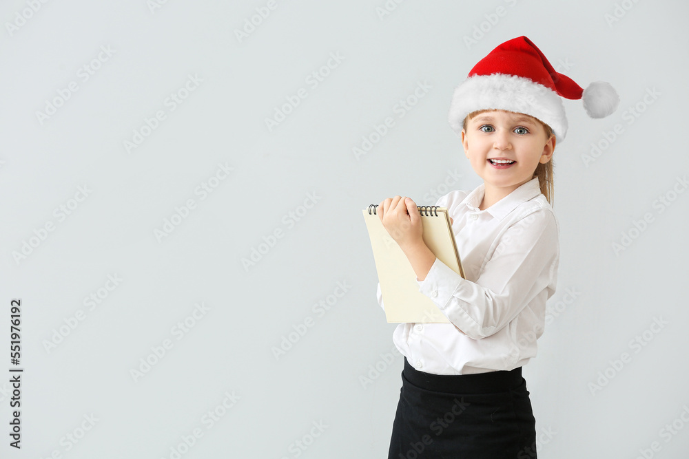 Cute little girl dressed as waiter in Santa hat on light background