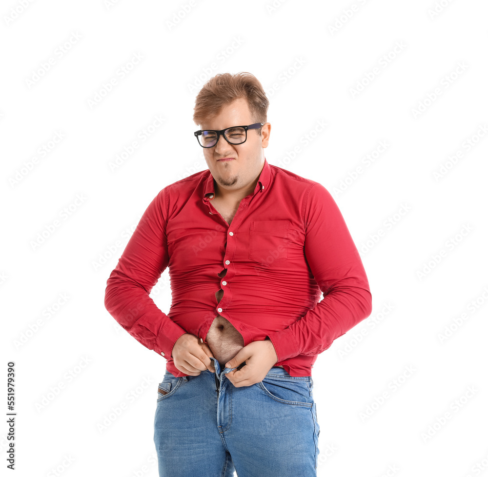 Young overweight man in tight shirt and jeans on white background