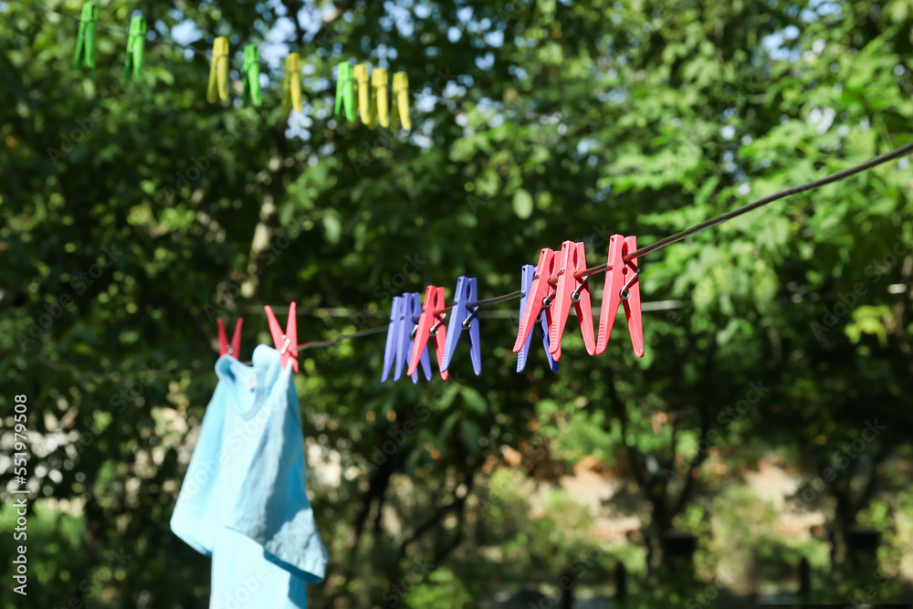 Many different clothespins hanging on rope outdoors