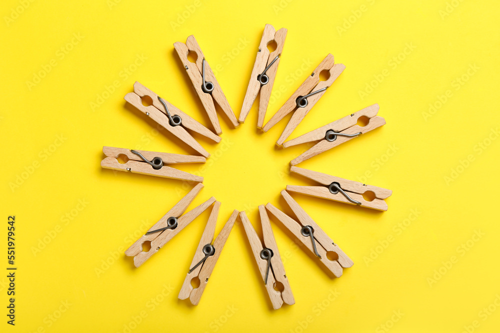 Composition with wooden clothespins on yellow background