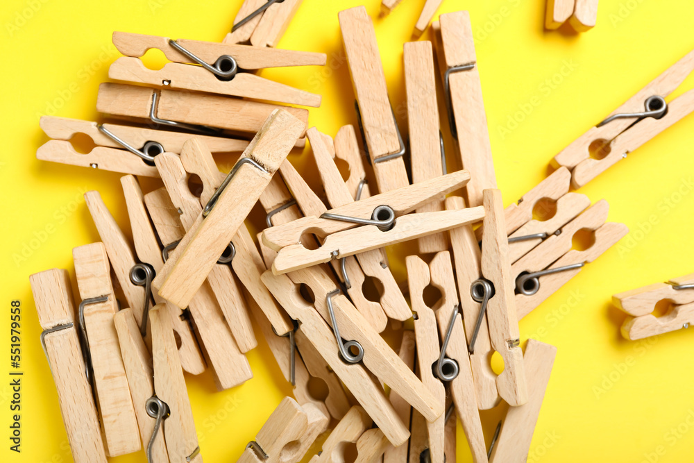 Heap of wooden clothespins on yellow background, closeup