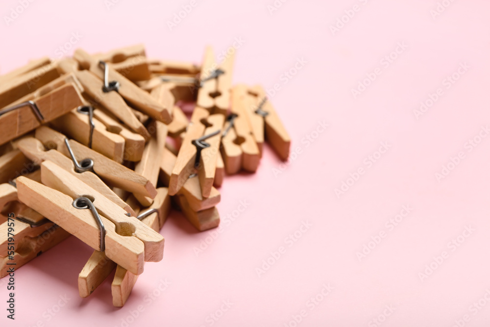 Heap of wooden clothespins on pink background, closeup