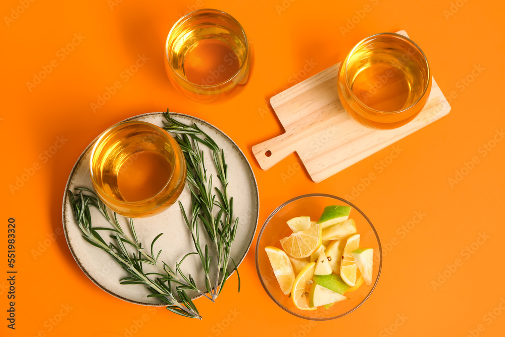 Glasses of fresh apple juice and rosemary on color background