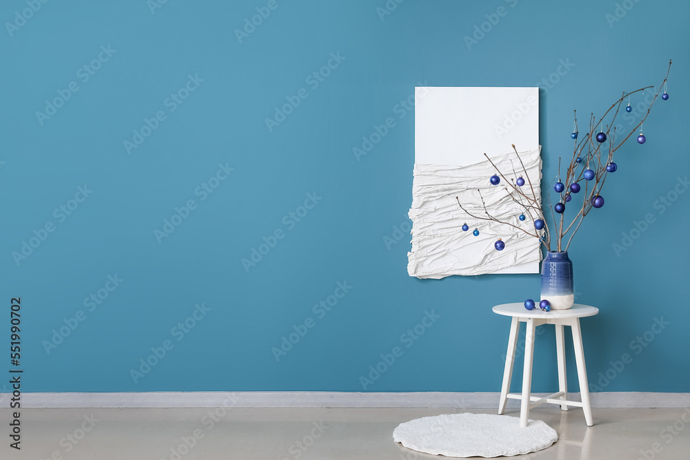 Vase with tree branches and Christmas balls on table in living room