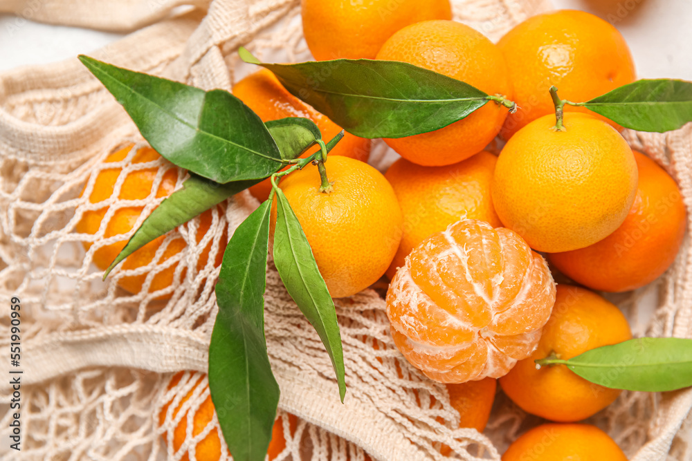 Shopping string bag with ripe tangerines and leaves, closeup