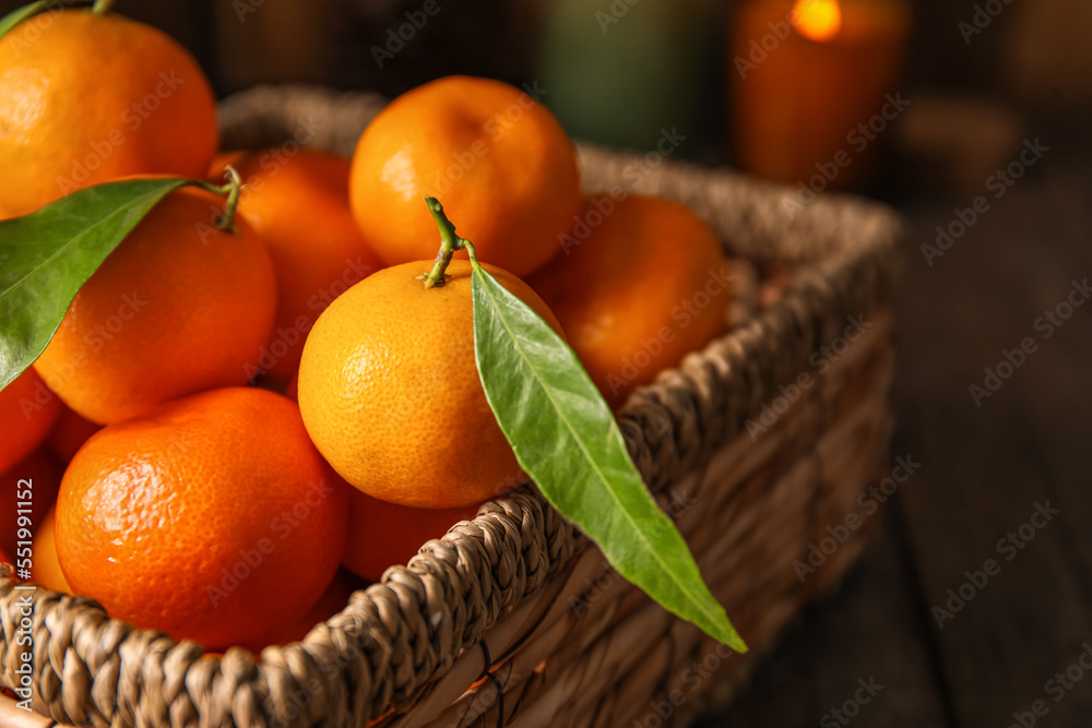 Basket with ripe tangerines on wooden table, closeup