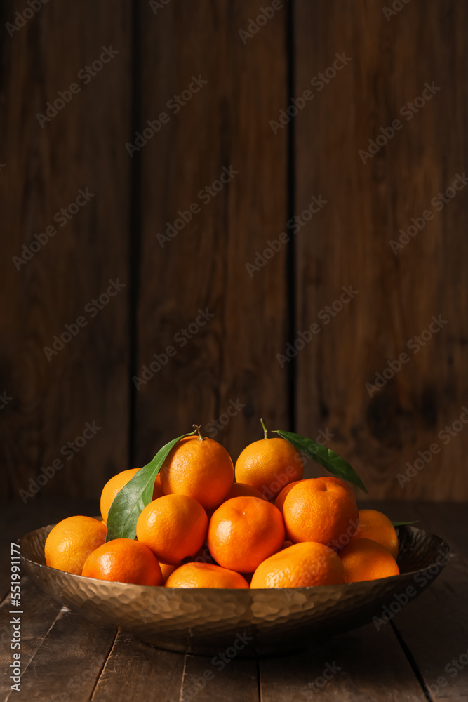 Plate with ripe tangerines on wooden table