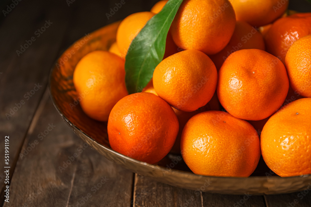 Plate with ripe tangerines on wooden table, closeup